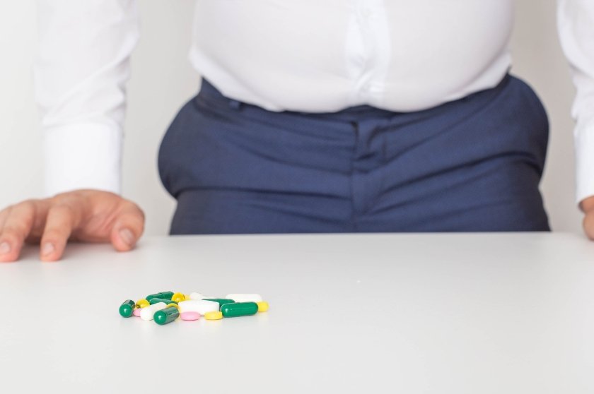 Homem sentado diante de comprimidos sobre a mesa, representando o uso de medicamentos no tratamento da incontinência urinária após cirurgia de próstata.