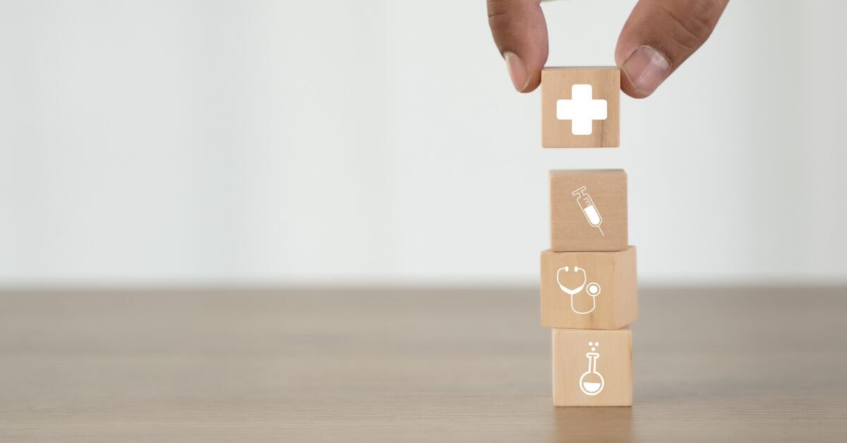 Blocos de madeira com ícones de saúde sendo empilhados, simbolizando cuidados preventivos e impacto do ambiente na longevidade.