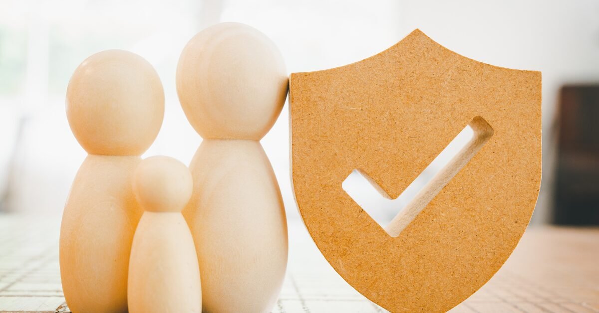 Família representada por figuras de madeira ao lado de escudo de proteção, simbolizando segurança, saúde preventiva e longevidade.