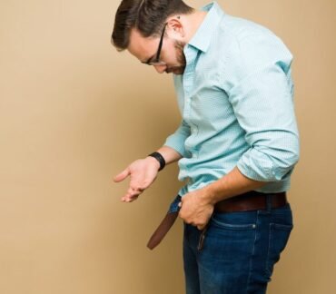 Homem de camisa xadrez azul preocupado com disfunção erétil olhando para baixo