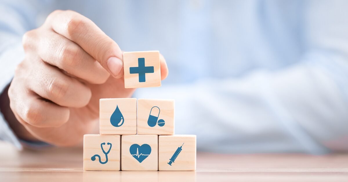 Blocos de madeira com ícones de saúde empilhados, representando como qualidade de vida, prevenção e ambiente impactam a longevidade.